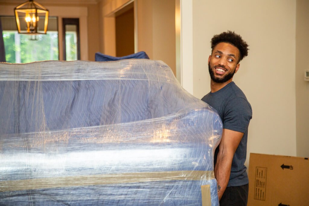 Mover, Cameron, carrying a wrapped sofa.
